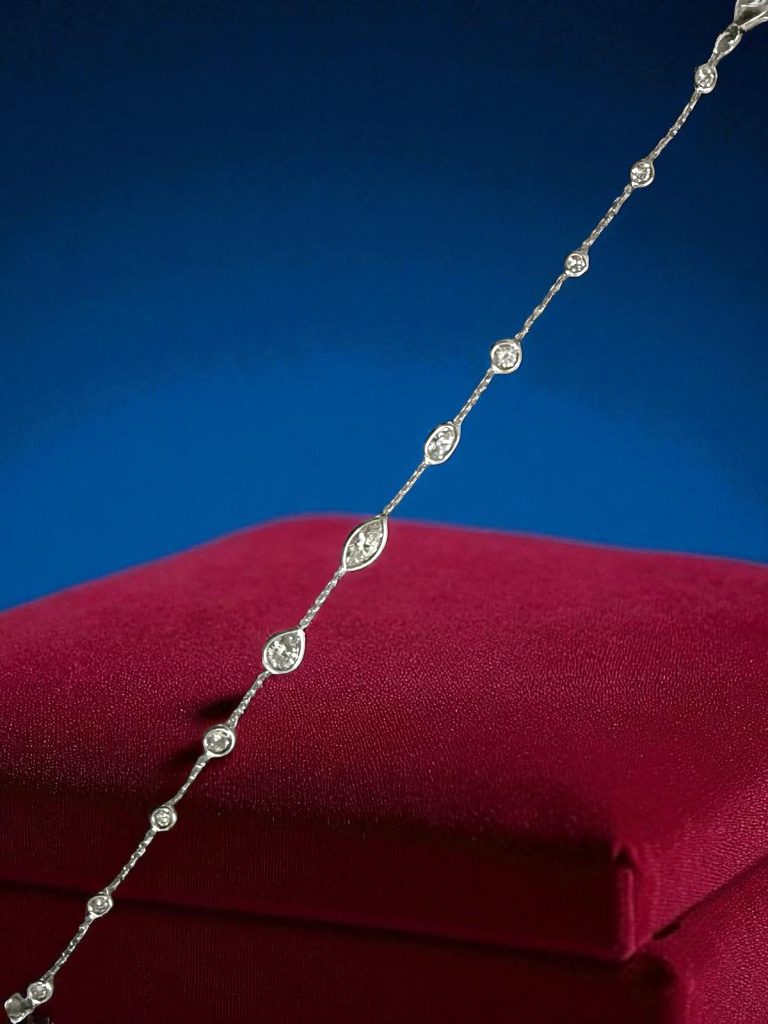 Elegant diamond necklace with alternating marquise and round cut diamonds set in a delicate silver chain, displayed on a luxurious red velvet cushion against a deep blue background. Perfect for jewelry collectors and investors.