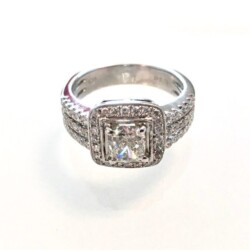 A stunning diamond ring featuring a square center stone surrounded by a halo of smaller diamonds, set in a sleek silver band. Perfect for engagements or special occasions, showcasing exquisite craftsmanship and timeless elegance. Rings