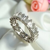 Stunning diamond eternity ring featuring baguette-cut stones, perfect for estate jewelry buyers and sellers. Elegant diamond eternity ring with baguette-cut stones on a satin fabric background.